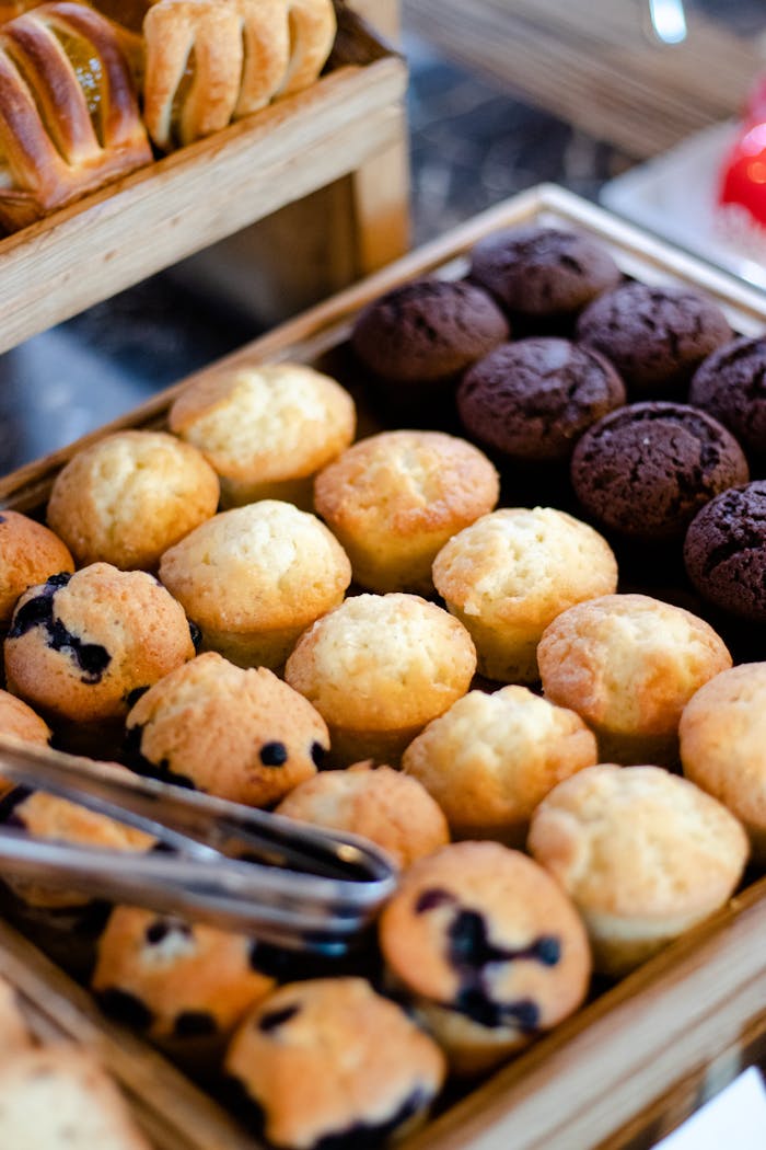 Close-up of various muffins beautifully arranged on a wooden tray, capturing a tempting display of baked goods.