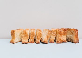 A close-up view of sliced rustic bread with a minimalist backdrop, showcasing texture and simplicity.